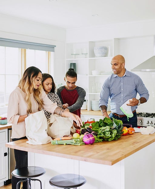 Wide shot of family unloading fresh produce in kitchen after shopping