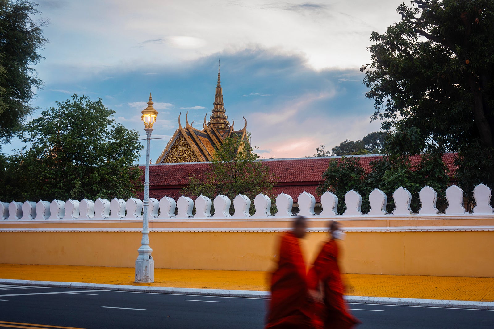 Two monks walking along street along the wall of the Royal Palace in Phnom Penh, Cambodia.