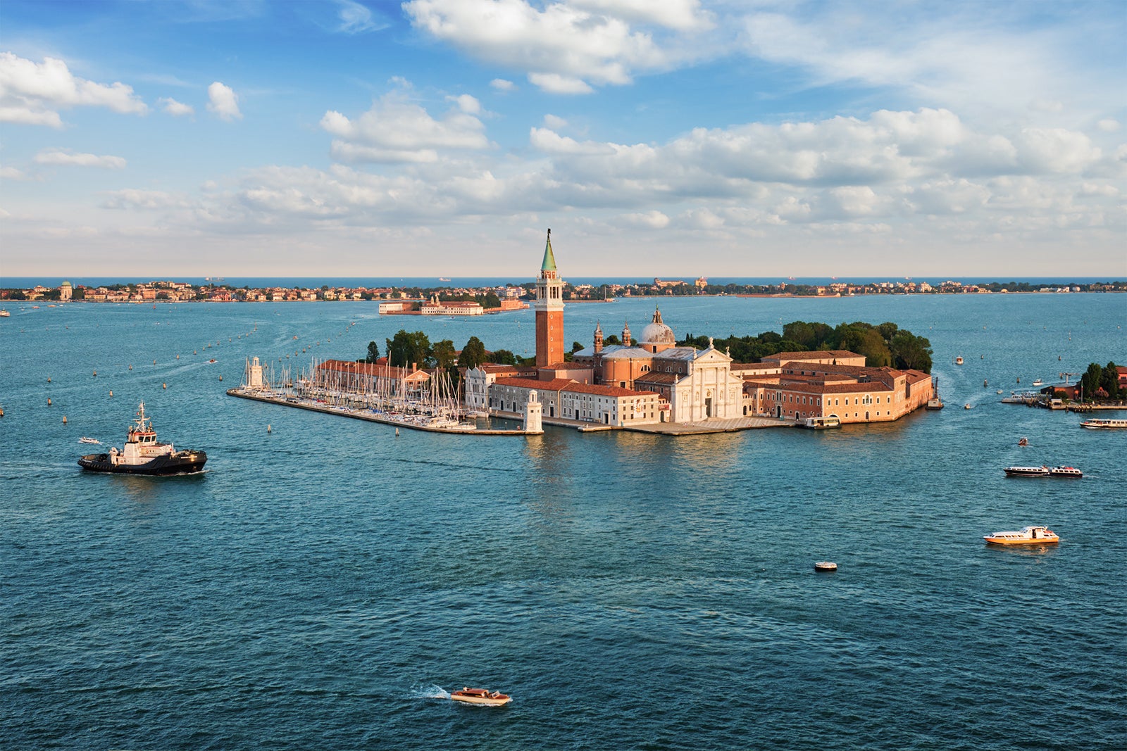 Famous Italy tourist destination - aerial view of Venice lagoon, San Giorgio di Maggiore church & San Marco square with boats and vaporetto on sunset from St Mark's Campanile bell tower, Venice, Italy