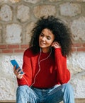 Woman with mobile phone and earphones outdoors.