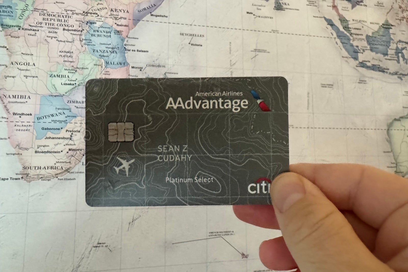 Why I've kept this American Airlines credit card in my wallet for years a hand holding a credit card in front of a map