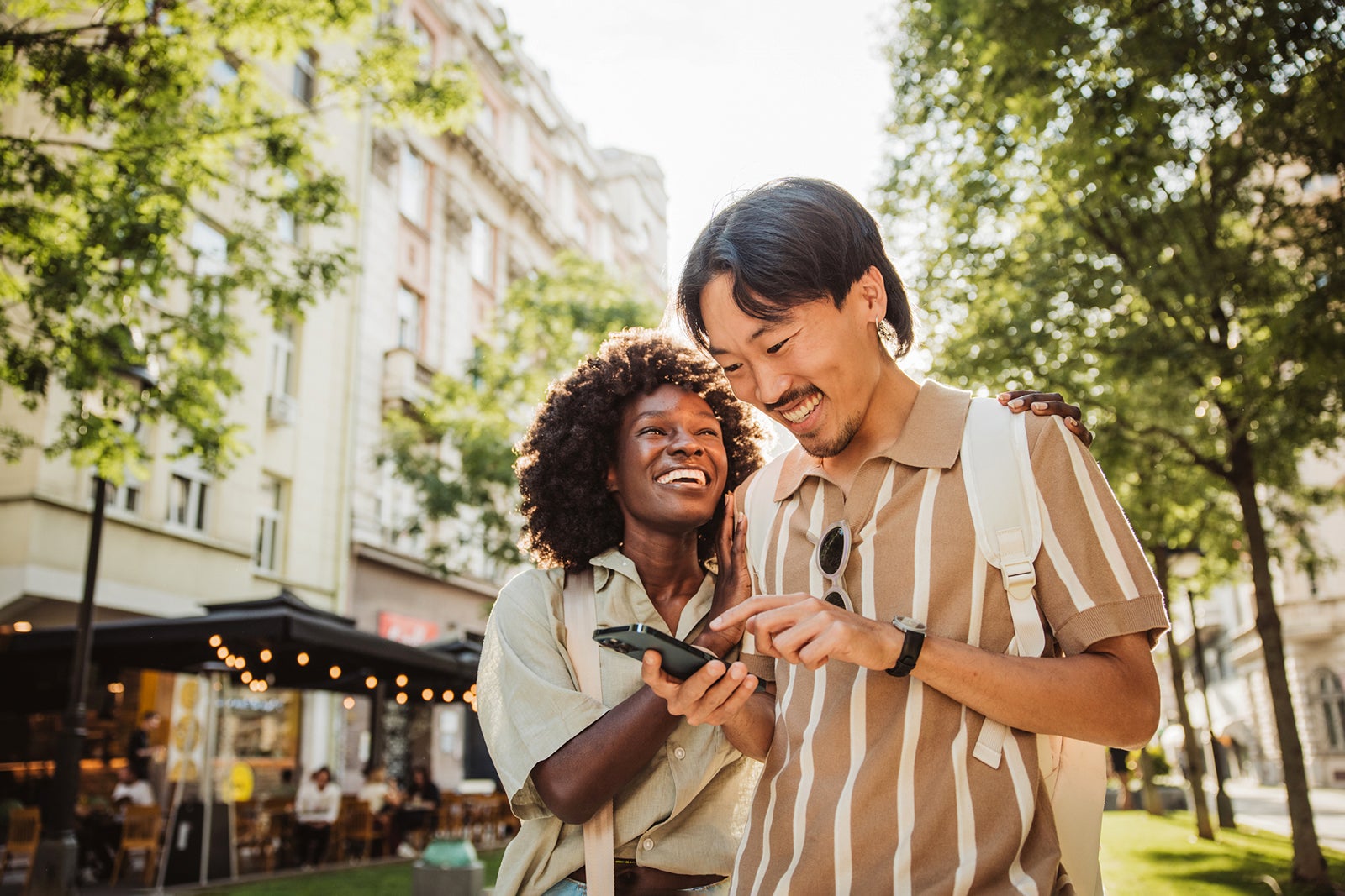 Young tourist couple, walking through the city and checking map on smart phone. Wearing casual clothes.