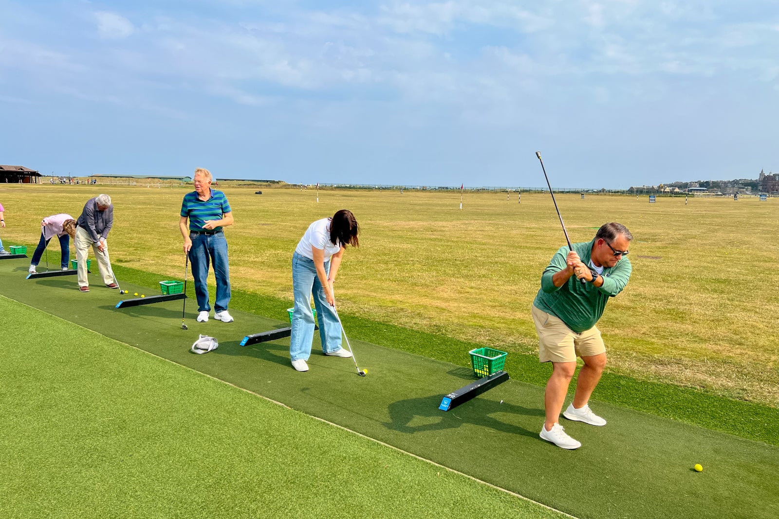 Tourgoers hitting golf balls at a practice range in St. Andrews, Scotland.