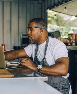 Mature male entrepreneur working on laptop by female colleague in food truck