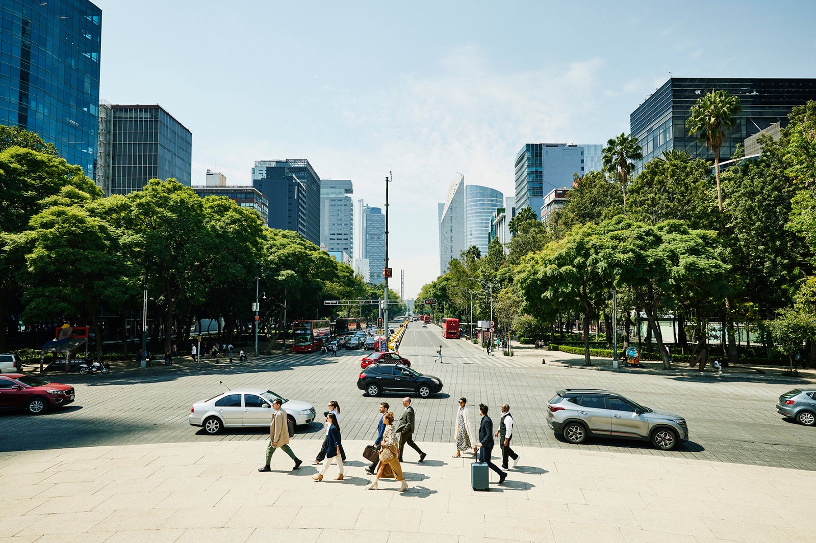 Extreme wide shot of business colleagues in discussion while walking on sidewalk of city boulevard