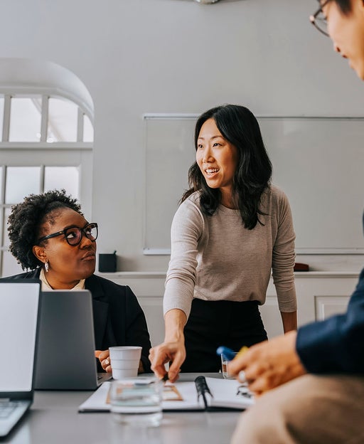 Female entrepreneur explaining business strategies to colleagues in meeting room at office