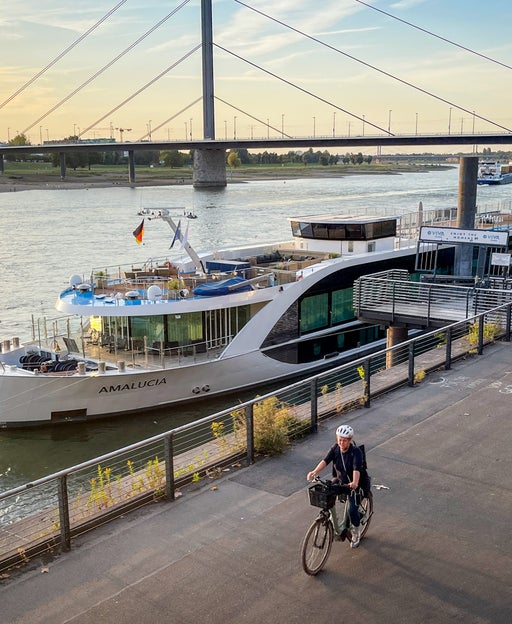 AmaWaterways AmaLucia docked at Dusseldorf, Germany at sunset with biker riding by