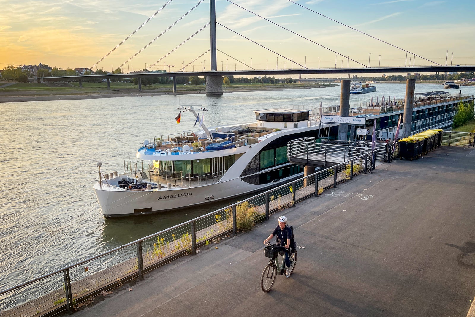 AmaWaterways AmaLucia docked at Dusseldorf, Germany at sunset with biker riding by