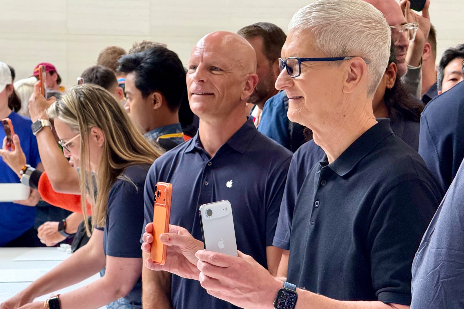 Tim Cook holds two iPhones at a press event