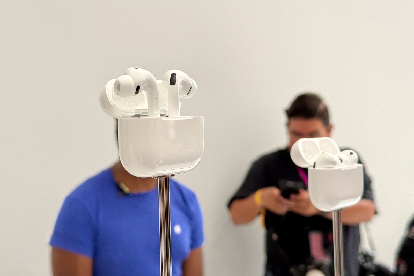 two sets of AirPods on display at a press event
