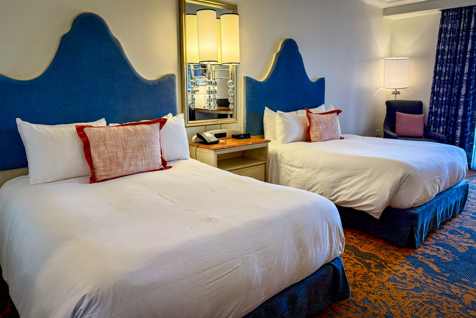 a hotel room with two beds with tall blue headboards