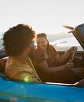 Young woman laughing while talking with boyfriend sitting in convertible car