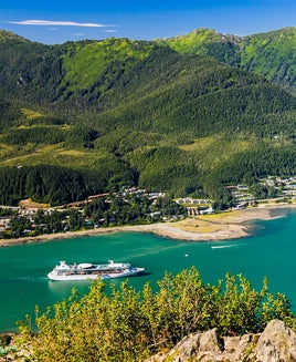 A luxury cruise ship sails along a narrow straight to reach Juneau, Alaska. on an August morning.