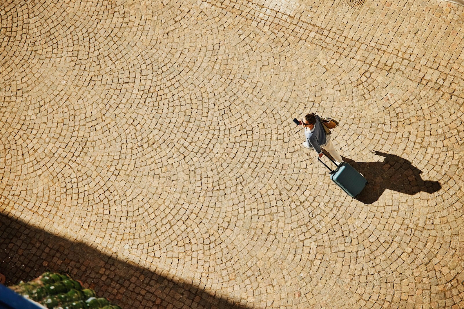 Woman carrying suitcase down empty street