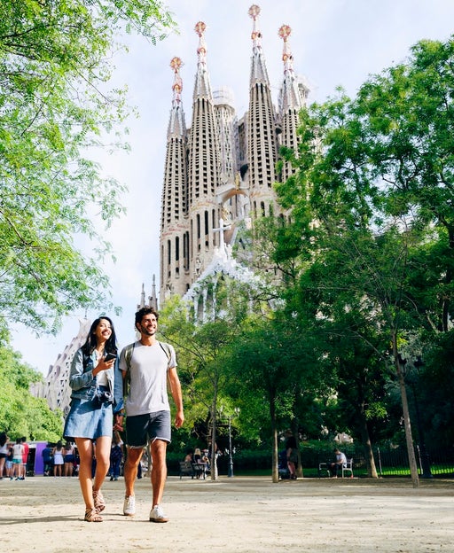 Smiling vacationers holding hands and walking in Barcelona