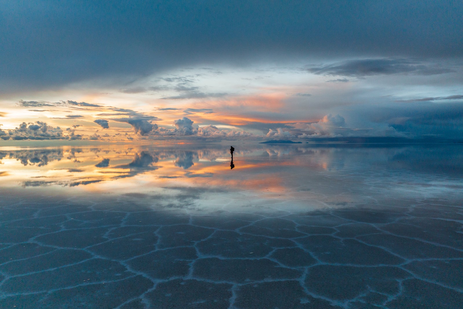 Low angle drone image at sunset showing one man walking on Salar de Uyuni, Bolivia