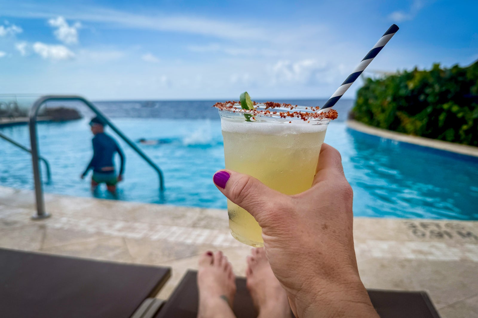 woman holding cocktail in front of the pool