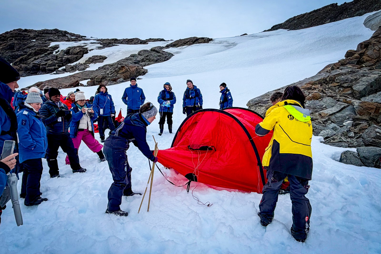 Guides from the expedition ship Roald Amundsen offer a demonstration on how to set up a tent on the ice.