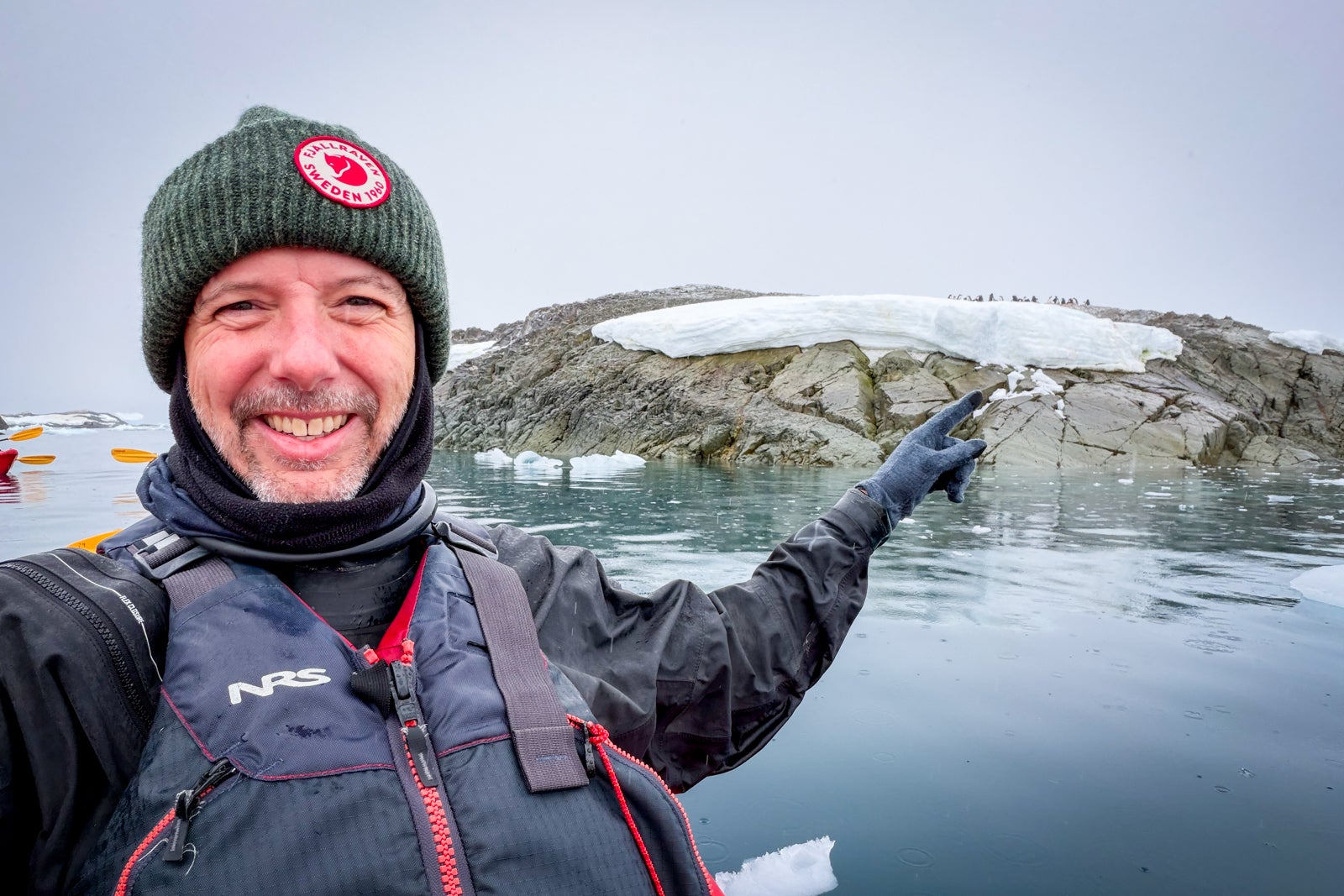 TPG's Gene Sloan points to a penguin colony on land during a kayaking outing.