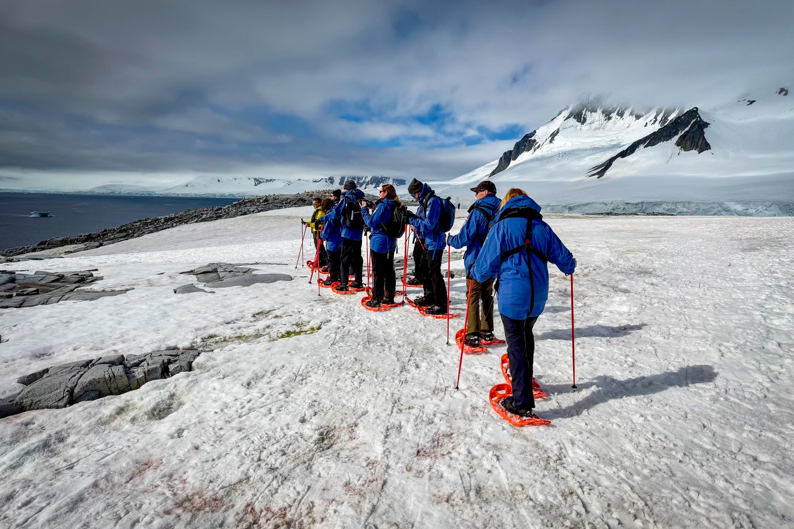 Passengers from the expedition cruise ship Roald Amundsen snowshoe in Antarctica.
