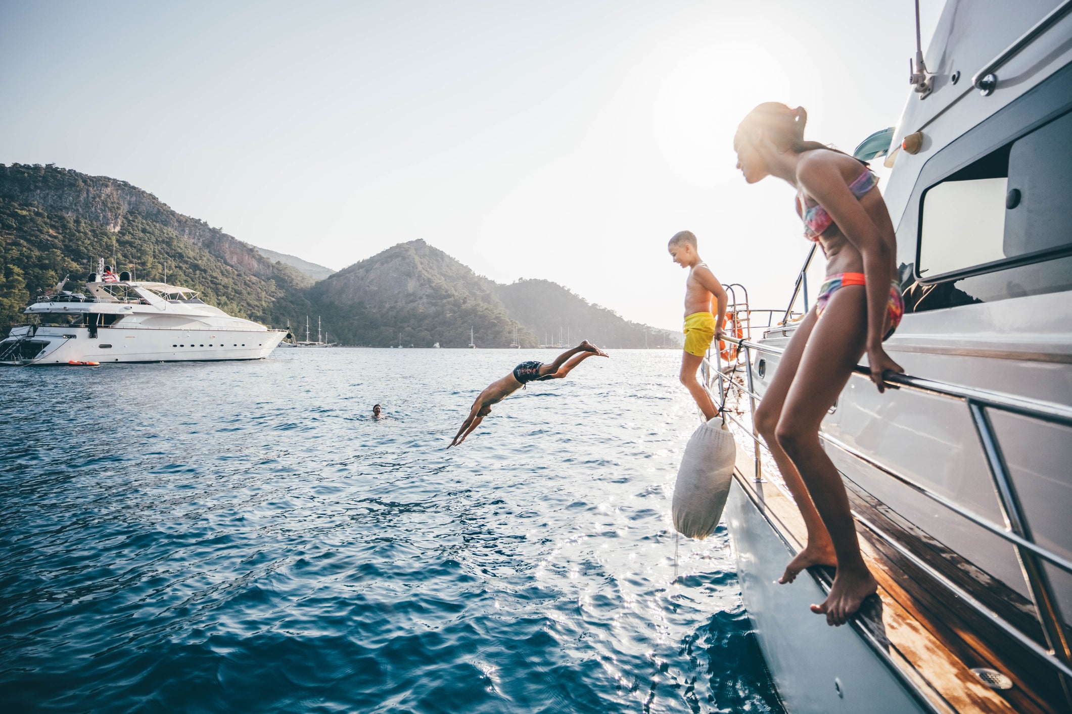 Family jumping in the water from yacht.