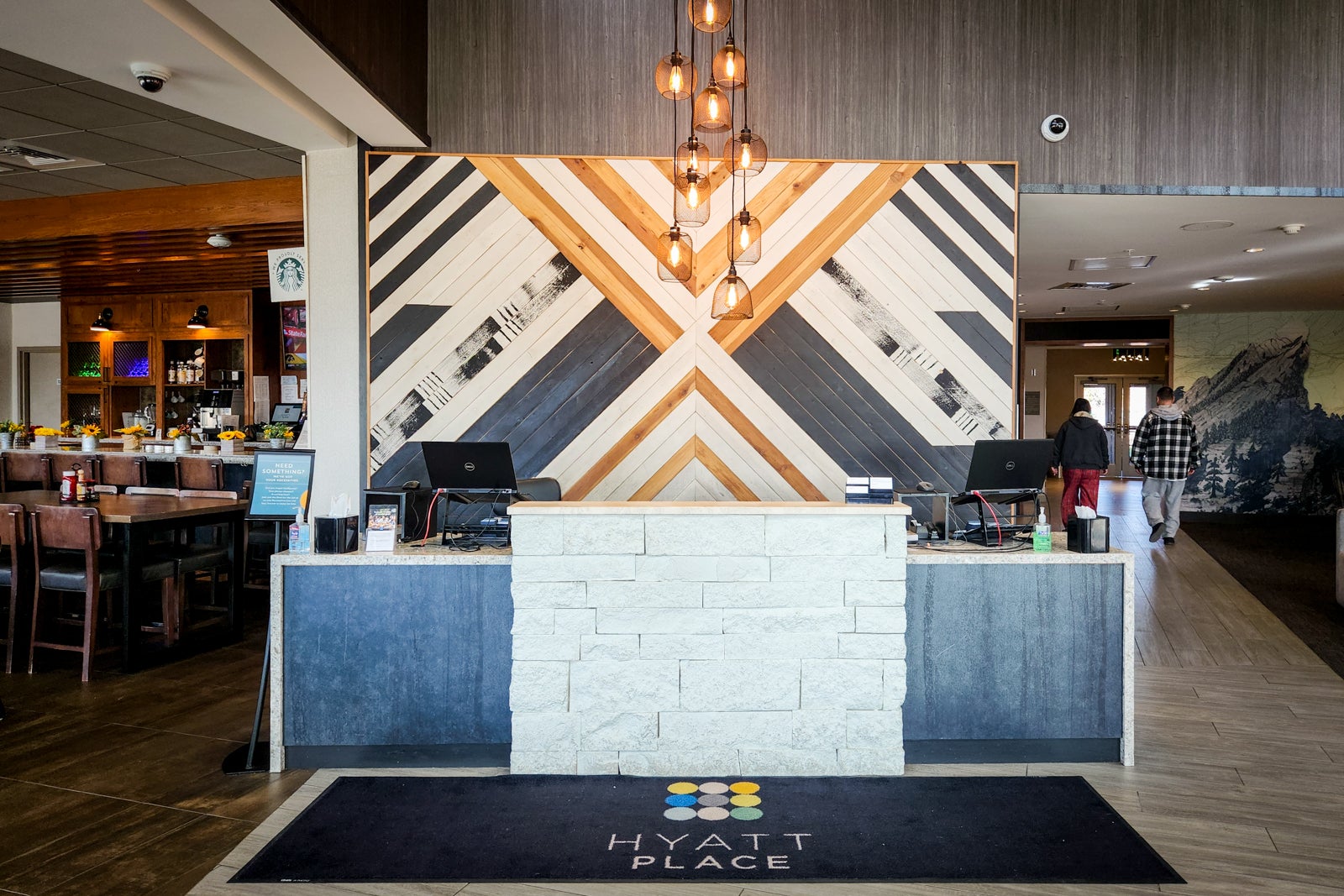 hotel front desk with Hyatt Place rug on floor and wood art on wall