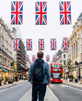 Rear view of man with backpack standing on Regent street decorated with British flags, London, UK