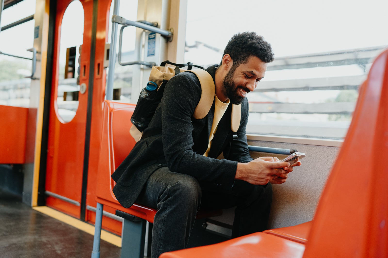 Handsome man traveling by city train, scrolling on a smartphone. Man heading home after a long day at work. The single man commutes alone. Single man using dating app.