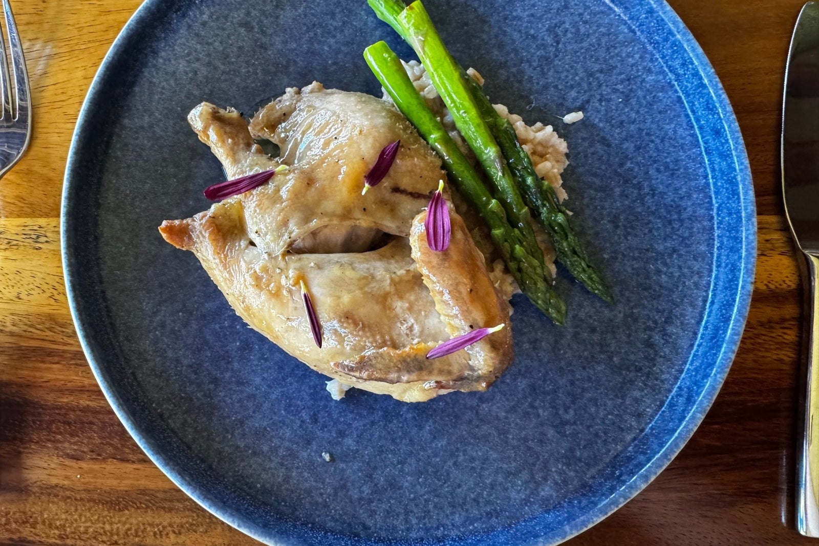 Chicken with asparagus on a blue plate and wooden table