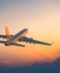 Passenger airplane flying above clouds during sunset