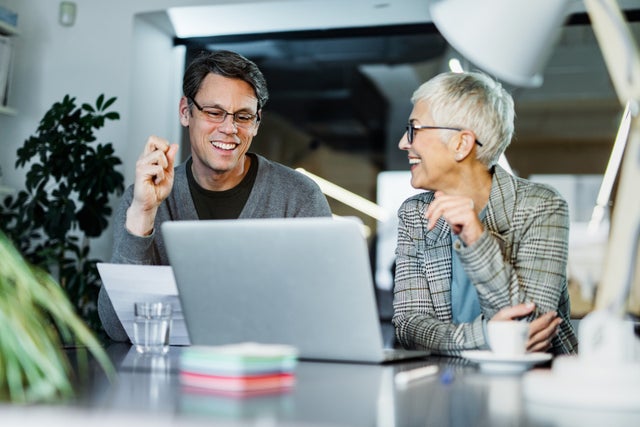 Happy business colleagues communicating while working on a computer in the office.