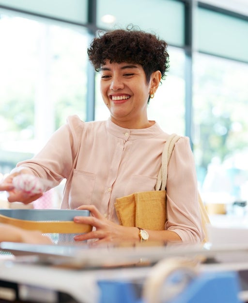 A woman paying for purchase in retail store and bring reusable bags